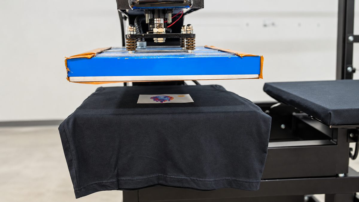 Heat press positioned over a DTF transfer on a garment